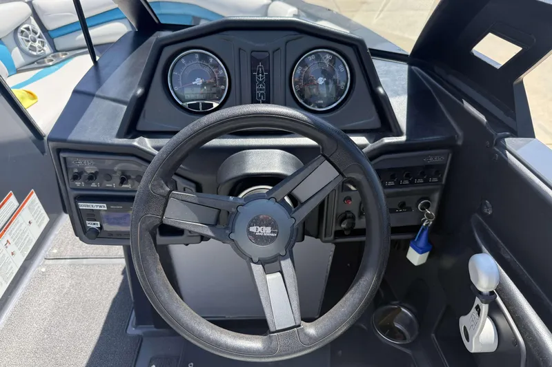 Slide: The Image of Steering wheel and dashboard of a 2016 Axis A22 boat, featuring gauges and controls. - 12