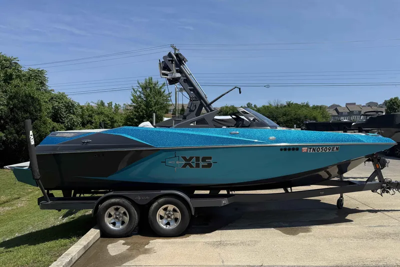 Slide: The Image of 2016 Axis A22 boat on trailer, vibrant blue color, parked outdoors. - 2