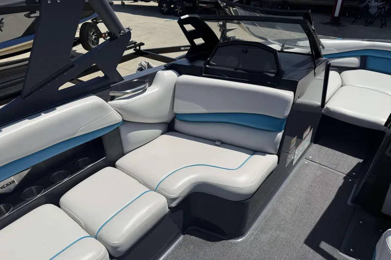 Slide: The Image of 2016 Axis A22 boat interior with gray and blue seating, cup holders, and dashboard. - 20