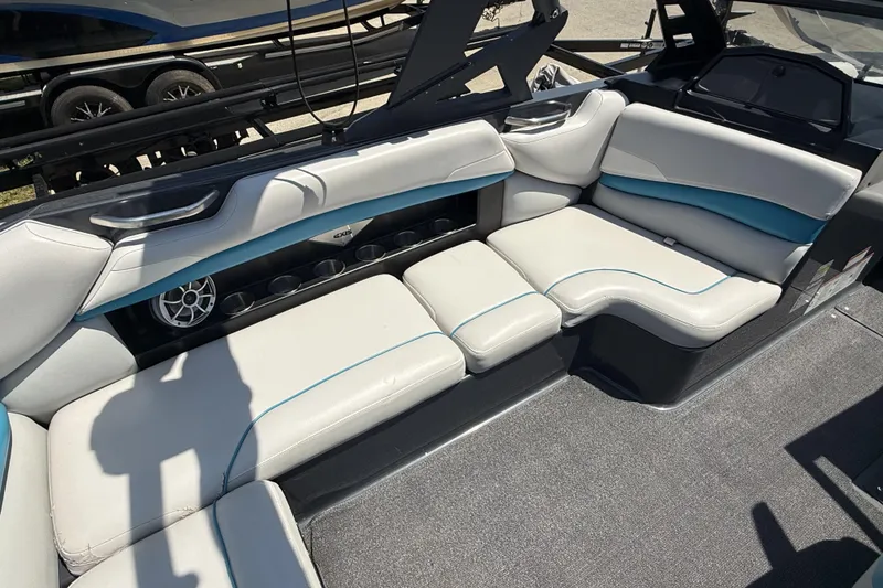 Slide: The Image of 2016 Axis A22 boat interior with white and blue seating, cup holders, and speaker. - 21