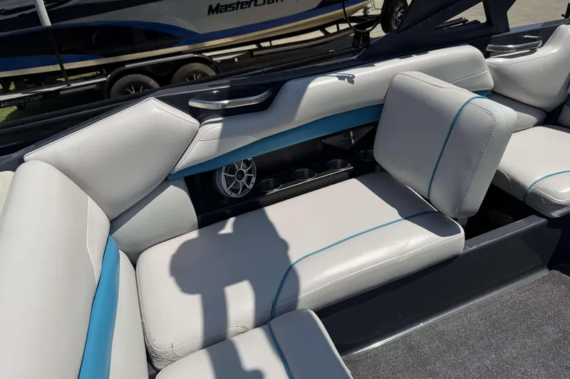 Slide: The Image of 2016 Axis A22 boat interior with white and blue seating, cup holders, and speaker. - 22