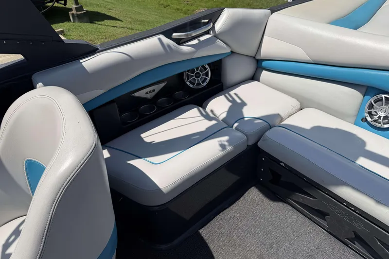 Slide: The Image of 2016 Axis A22 boat interior with white and blue seating, cup holders, and speakers. - 23