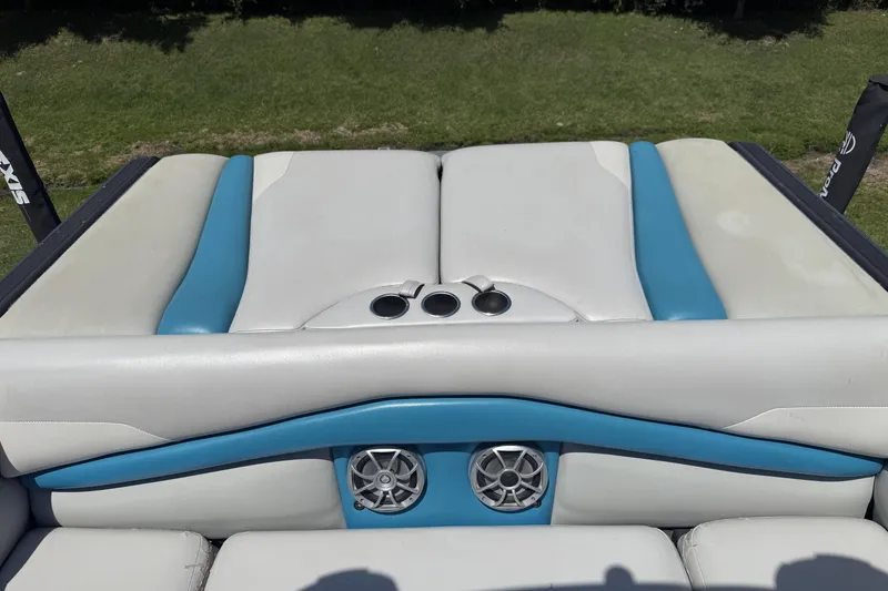 Slide: The Image of 2016 Axis A22 boat interior with blue and white seating, cup holders, and speakers. - 25