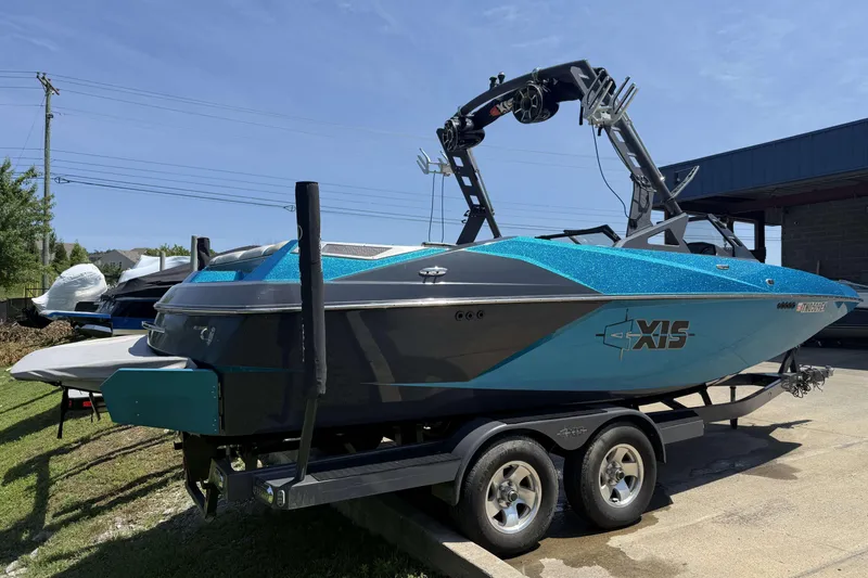 Slide: The Image of 2016 Axis A22 boat with blue and gray design on a trailer, parked outdoors. - 3