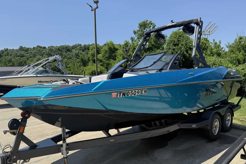 Slide: The Image of 2016 Axis A22 boat in vibrant blue on a trailer, surrounded by greenery. - 4