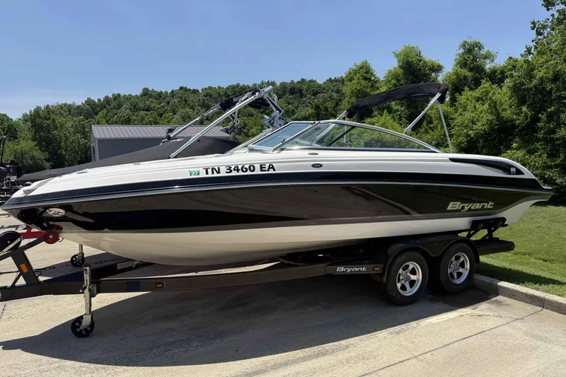 The Image of 2010 Bryant 233 boat on trailer, parked outdoors with lush greenery background. - 0