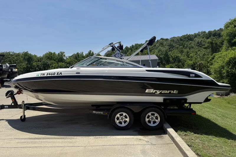 Slide: The Image of 2010 Bryant 233 boat on trailer, parked outdoors with lush greenery in the background. - 1