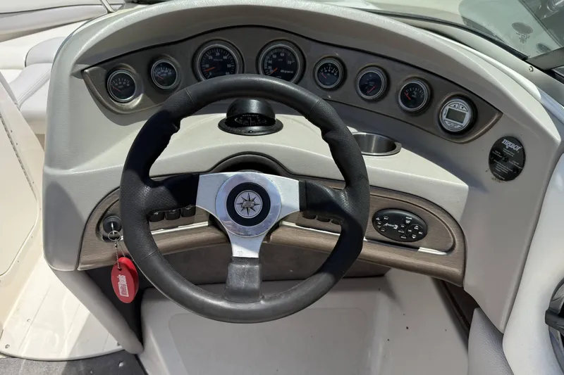 Slide: The Image of Steering wheel and dashboard of a 2010 Bryant 233 boat, featuring multiple gauges. - 10