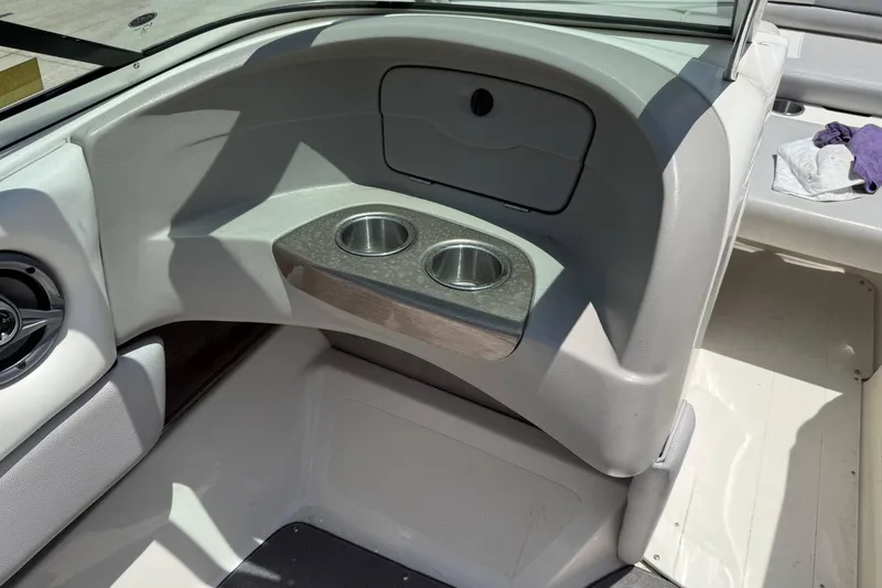 Slide: The Image of Interior of a 2010 Bryant 233 boat featuring dual cup holders and seating area. - 13