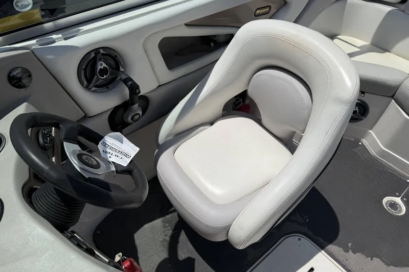 Slide: The Image of Steering area of a 2010 Bryant 233 boat with white seating and controls. - 9