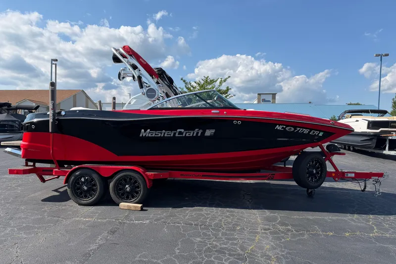 Slide: The Image of 2021 Masercraft XT22 boat on trailer, red and black design, parked outdoors. - 2