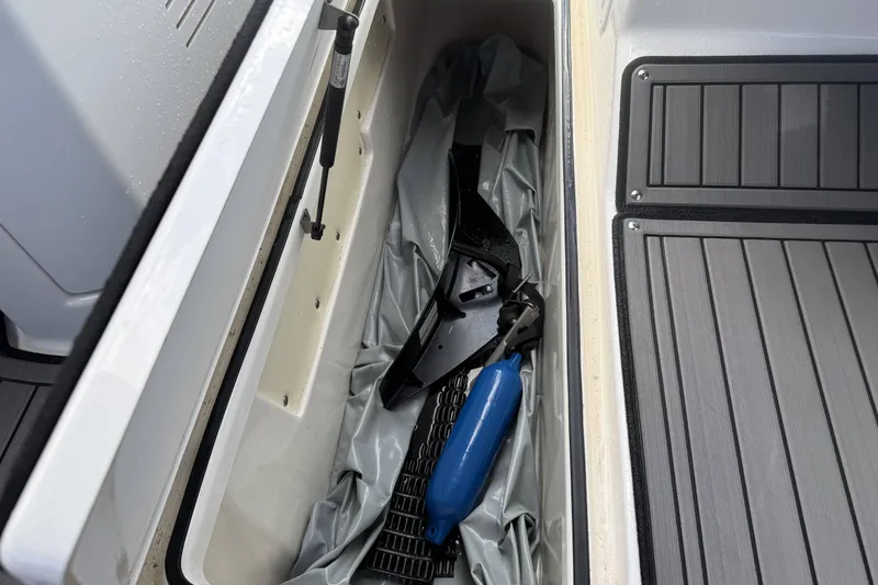Slide: The Image of 2018 Yamaha Boats 242X E-Series interior with seating and steering wheel, docked in a marina. - 20