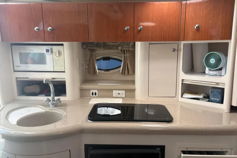 Slide: The Image of 2000 Monterey 322 Cruiser kitchen with microwave, sink, stove, and storage cabinets. - 34