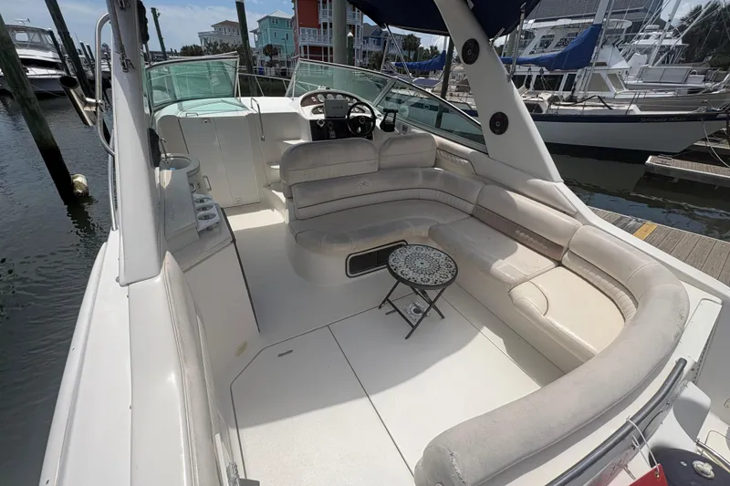 Slide: The Image of 2000 Monterey 322 Cruiser boat interior with seating and small table at marina. - 7