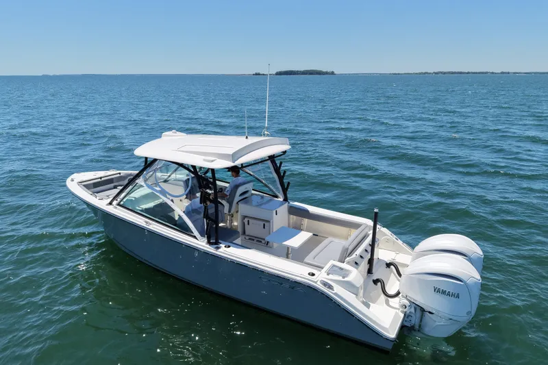 Slide: The Image of 2024 Cobia 280 Dual Console boat on open water, featuring twin Yamaha engines. - 1