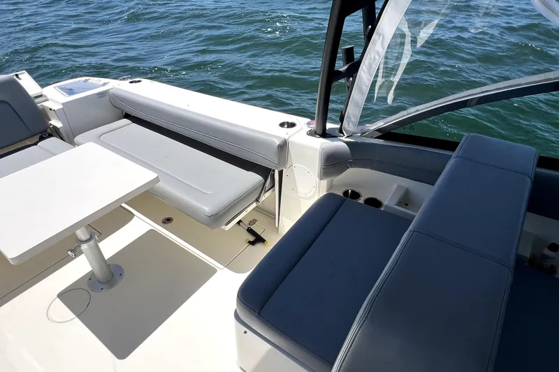 Slide: The Image of 2024 Cobia 280 Dual Console boat interior with seating and table on water. - 14