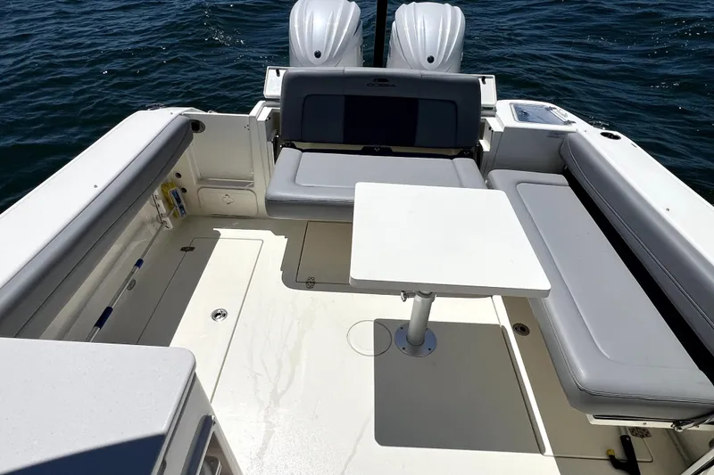 Slide: The Image of 2024 Cobia 280 Dual Console boat interior with seating and table on water. - 17