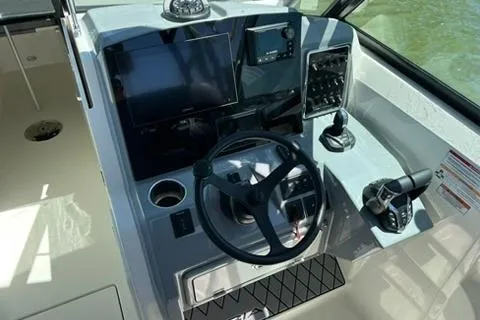 Slide: The Image of 2024 Cobia 280 Dual Console boat helm with steering wheel and navigation controls. - 19