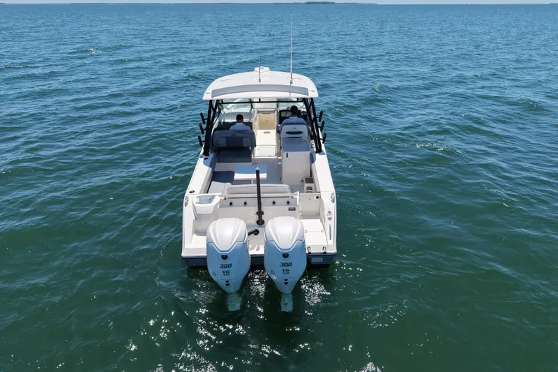 Slide: The Image of 2024 Cobia 280 Dual Console boat cruising on open water, rear view. - 2