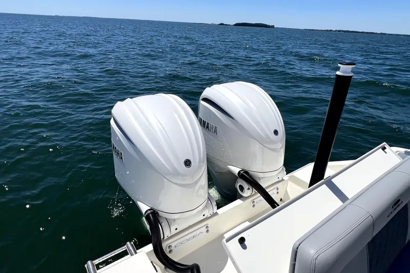 Slide: The Image of 2024 Cobia 280 Dual Console with twin Yamaha outboard engines on open water. - 22