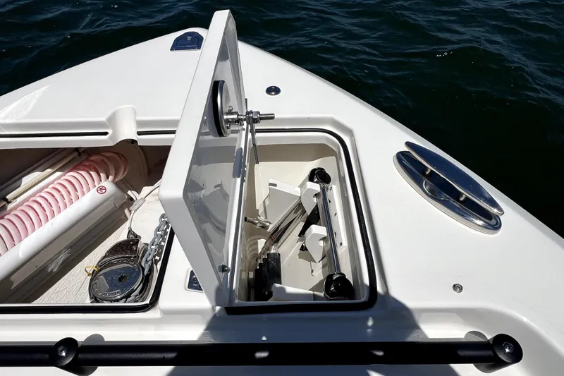 Slide: The Image of 2024 Cobia 280 Dual Console anchor compartment with open hatch, showcasing marine equipment. - 23