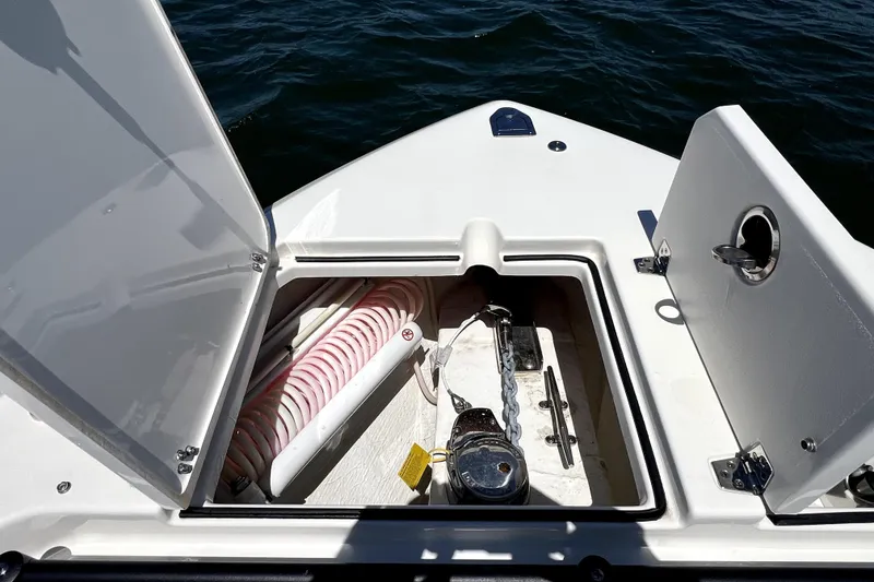 Slide: The Image of 2024 Cobia 280 Dual Console anchor storage compartment with open hatches on the water. - 24
