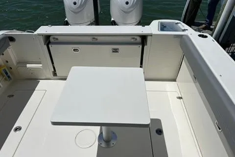 Slide: The Image of 2024 Cobia 280 Dual Console boat interior with table and twin engines. - 25