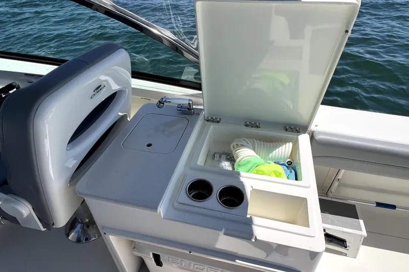 Slide: The Image of 2024 Cobia 280 Dual Console boat interior with open storage compartment and sink. - 26