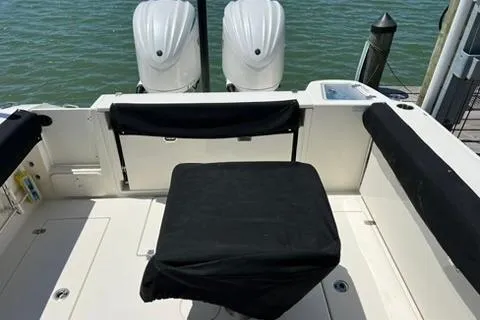 Slide: The Image of 2024 Cobia 280 Dual Console boat with twin engines, docked by the water. - 28