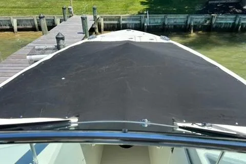 Slide: The Image of 2024 Cobia 280 Dual Console boat docked, featuring a covered bow area. - 29