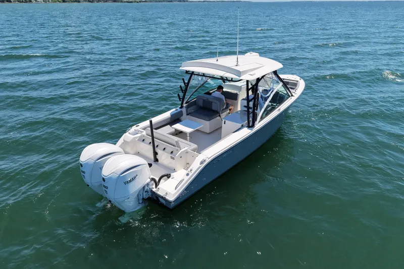 Slide: The Image of 2024 Cobia 280 Dual Console boat cruising on open water with twin Yamaha engines. - 3