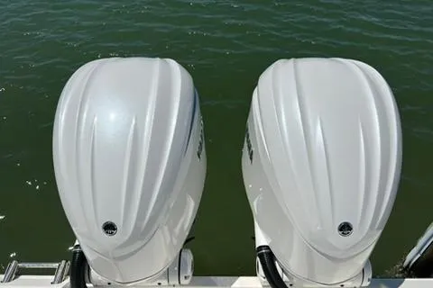 Slide: The Image of 2024 Cobia 280 Dual Console boat with twin outboard engines on water. - 30