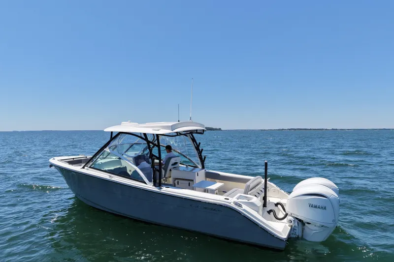 Slide: The Image of 2024 Cobia 280 Dual Console boat on open water, featuring twin Yamaha engines. - 4