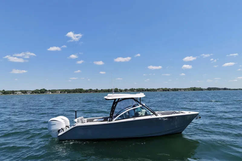Slide: The Image of 2024 Cobia 280 Dual Console boat on a sunny lake with clear skies. - 5
