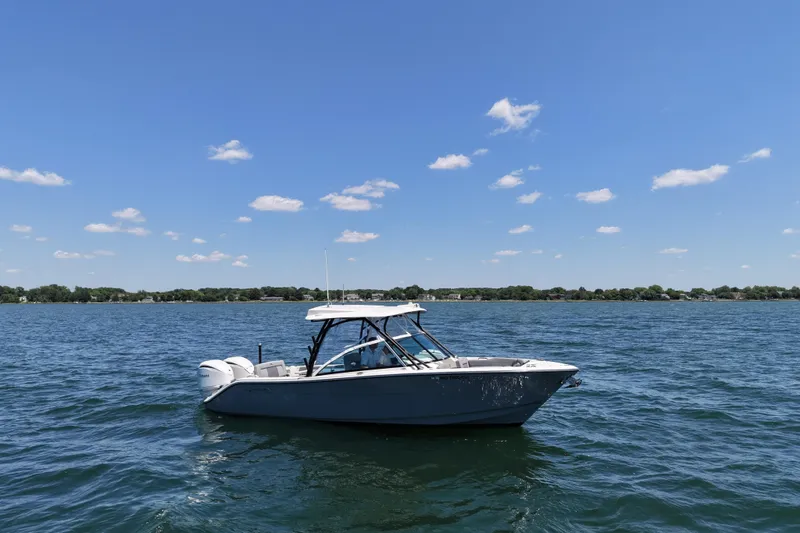 Slide: The Image of 2024 Cobia 280 Dual Console boat on a sunny lake with clear skies. - 6