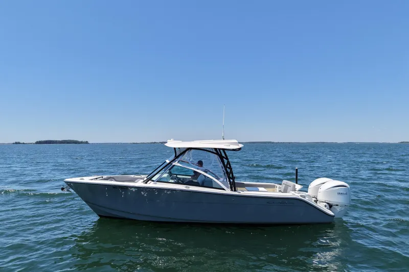 Slide: The Image of 2024 Cobia 280 Dual Console boat cruising on open water under clear blue sky. - 9