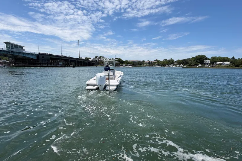 Slide: The Image of 2017 Everglades 243 Center Console boat on calm water near a bridge under a blue sky. - 22