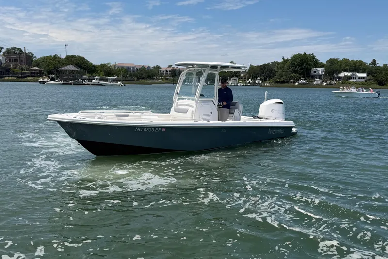 Slide: The Image of 2017 Everglades 243 Center Console boat on calm water, with scenic shoreline background. - 6