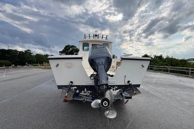 Slide: The Image of 2003 Parker 2120 Sport Cabin boat with outboard motor, parked under cloudy sky. - 10