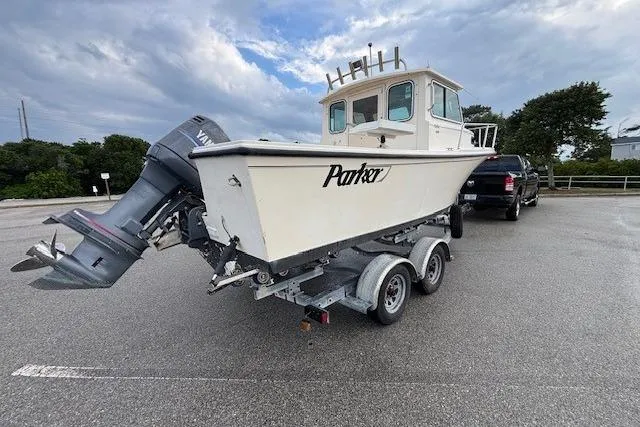 Slide: The Image of 2003 Parker 2120 Sport Cabin boat on trailer, parked outdoors under cloudy sky. - 12