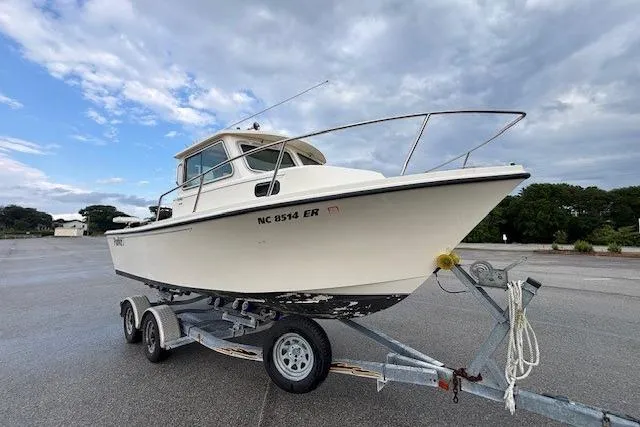 Slide: The Image of 2003 Parker 2120 Sport Cabin boat on trailer, parked outdoors under cloudy sky. - 14