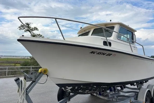 Slide: The Image of 2003 Parker 2120 Sport Cabin boat on trailer, parked outdoors under cloudy sky. - 2