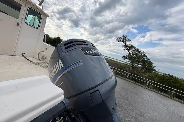 Slide: The Image of 2003 Parker 2120 Sport Cabin boat with Yamaha V6 150 engine, parked under cloudy sky. - 9