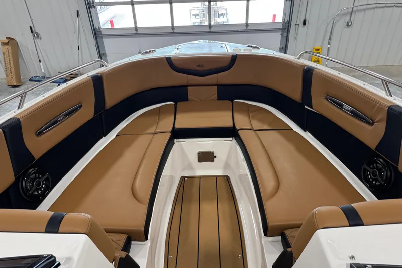 Slide: The Image of 2023 Chaparral 307 SSX boat interior with tan and black seating in a showroom. - 12