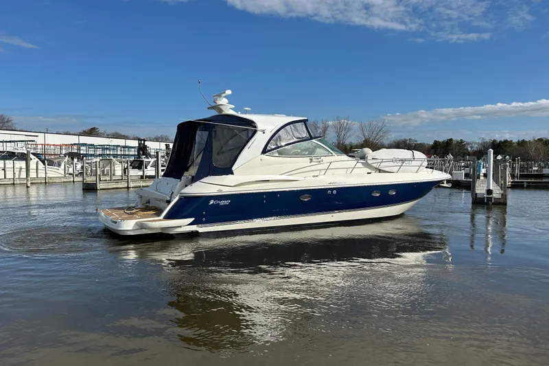 Slide: The Image of 2005 Cruisers Yachts 440 Express in marina, blue and white design, clear sky background. - 13
