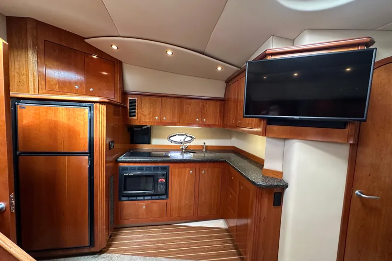 Slide: The Image of Luxurious 2005 Cruisers Yachts 440 Express kitchen with wood cabinetry and modern appliances. - 28