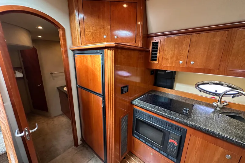 Slide: The Image of 2005 Cruisers Yachts 440 Express kitchen with wood cabinetry, microwave, and sink. - 29