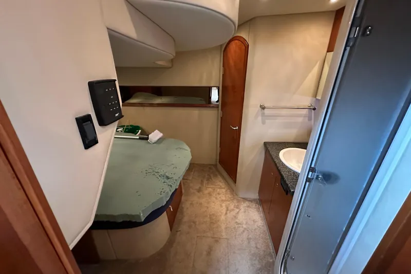 Slide: The Image of 2005 Cruisers Yachts 440 Express interior cabin with bed, sink, and wooden door. - 30