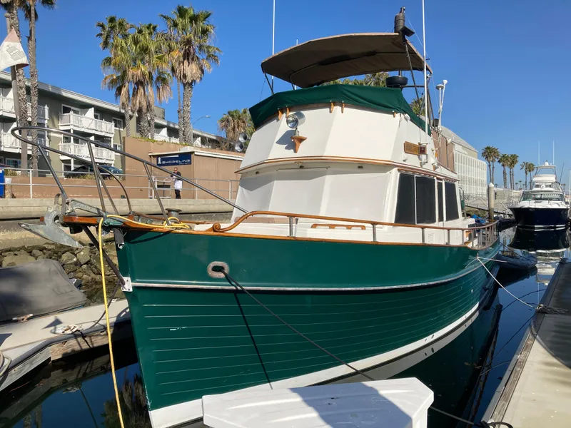 Slide: The Image of 1985 Grand Banks 42 Classic yacht docked at marina, green hull, sunny day, palm trees in background. - 1