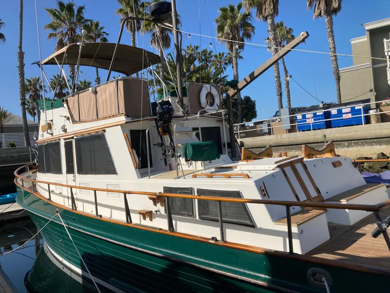 Slide: The Image of 1985 Grand Banks 42 Classic yacht docked, featuring green hull and wooden accents, surrounded by palm trees. - 7